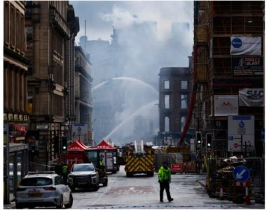 Firefighters spraying water on a smoking building on a city street