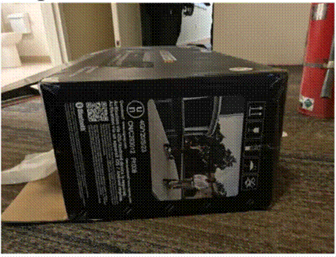 Cardboard e-scooter shipping box on a hallway floor beside a red fire extinguisher
